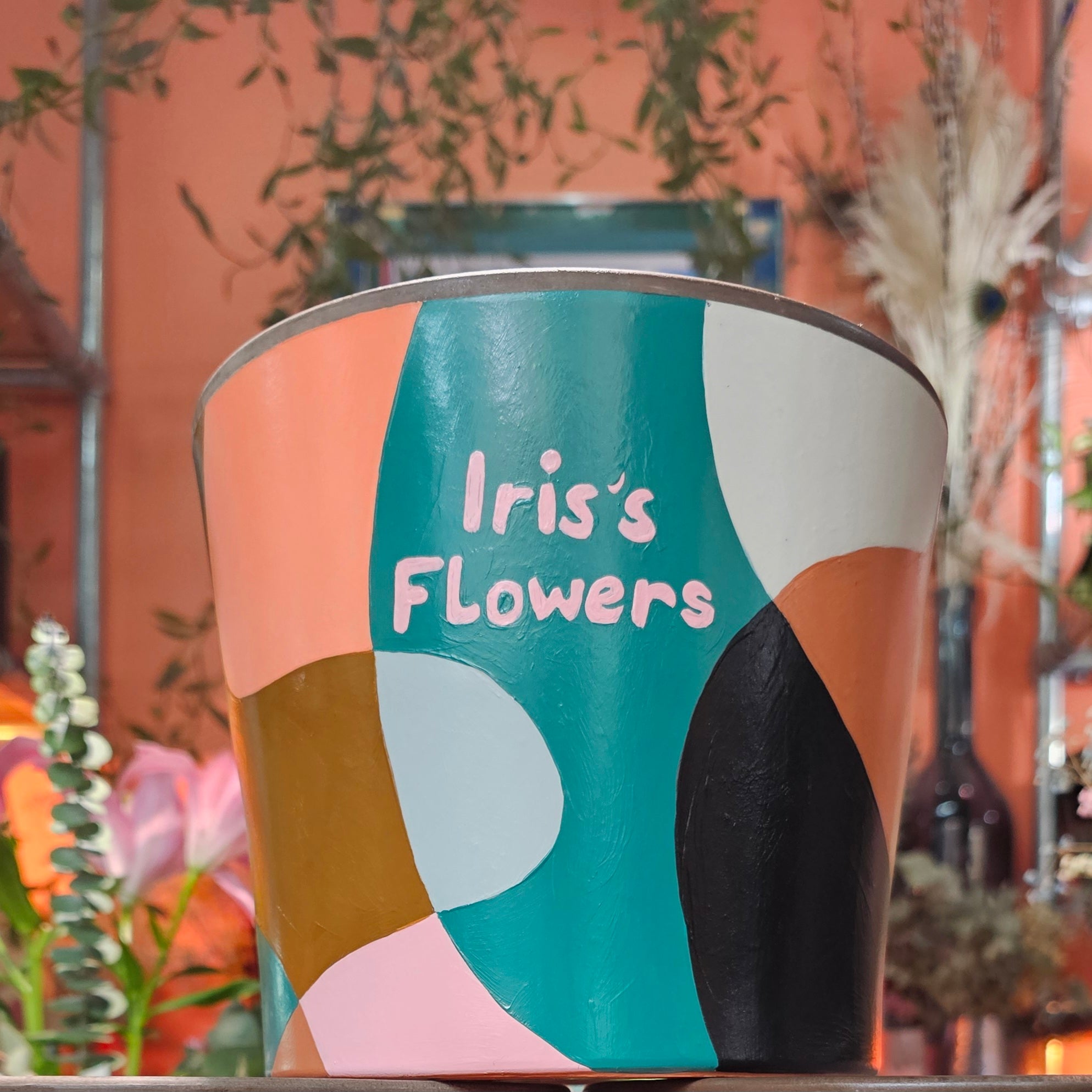 Colorful plant pot with 'Iris's Flowers' text painted 